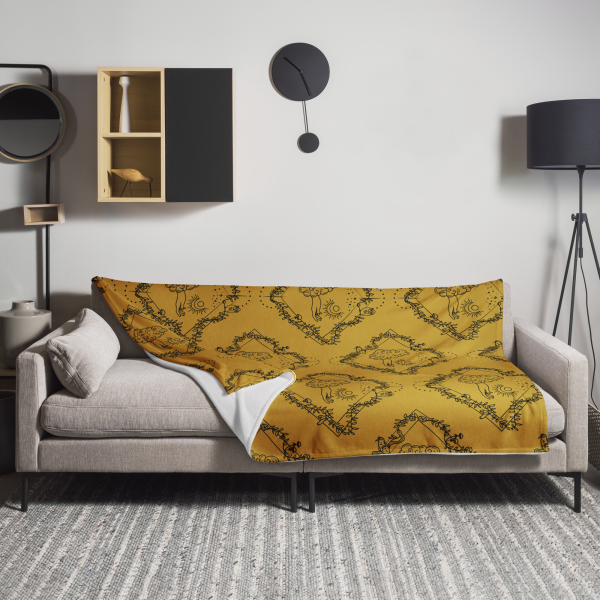 Gold throw blanket draped across a gray mod sofa in a minimalist living room with lamp, shelving, and black wall clock.